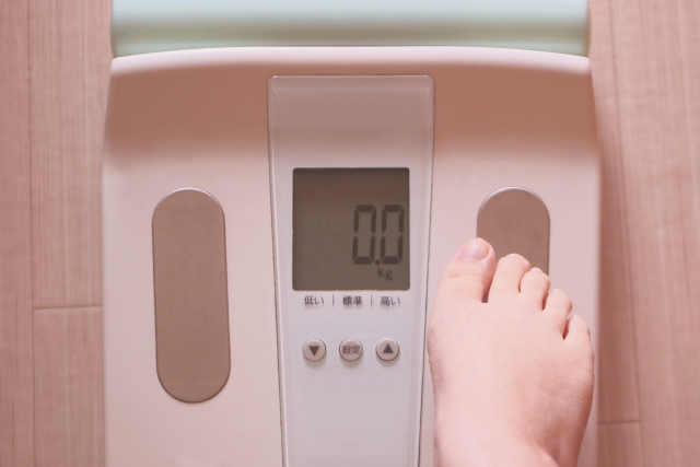 体重計に片足を乗せる女性