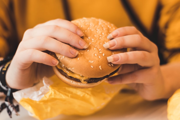 ハンバーガーをつかむ女性の手