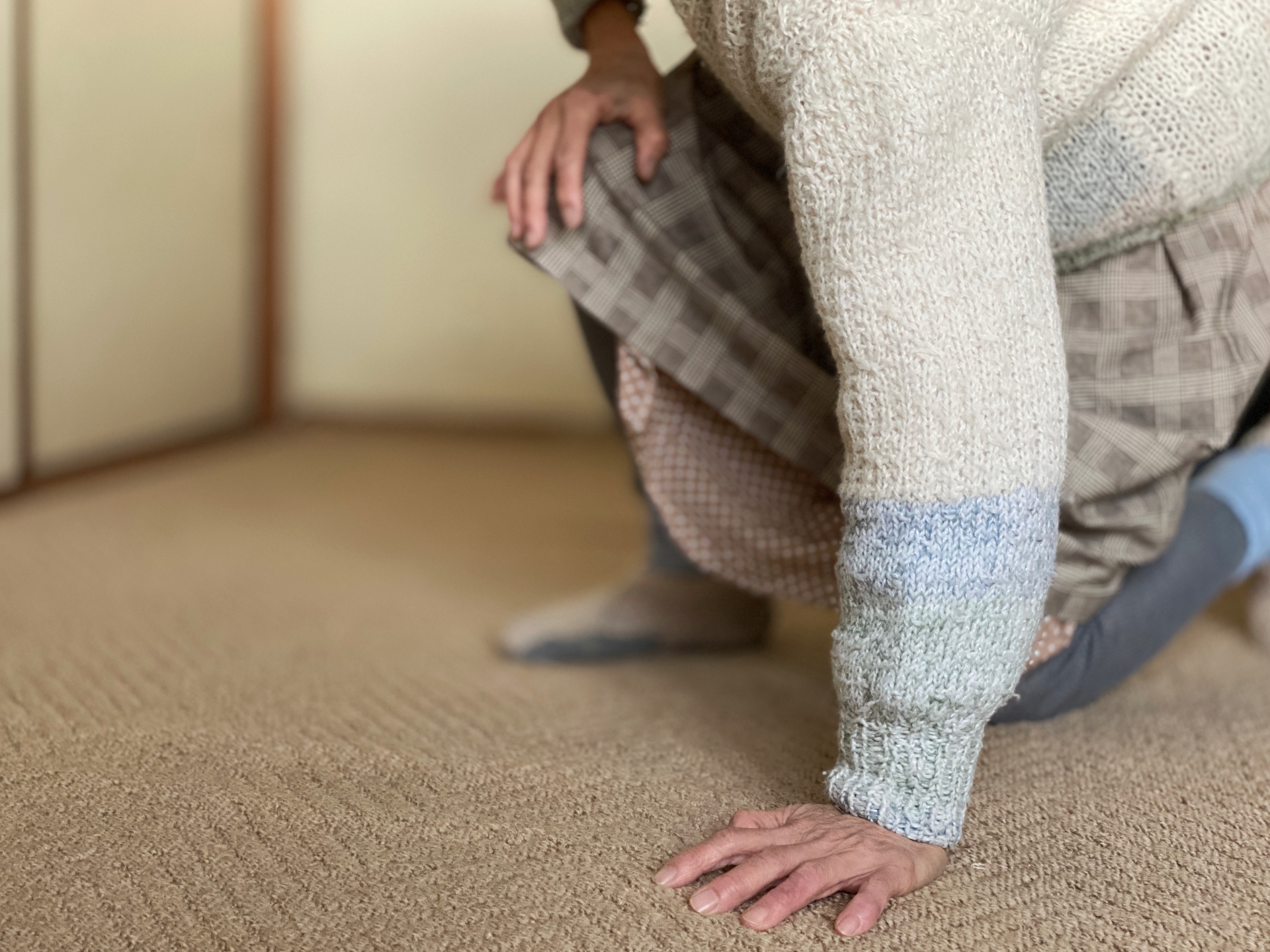 手をついて立ちあがろうとする高齢者