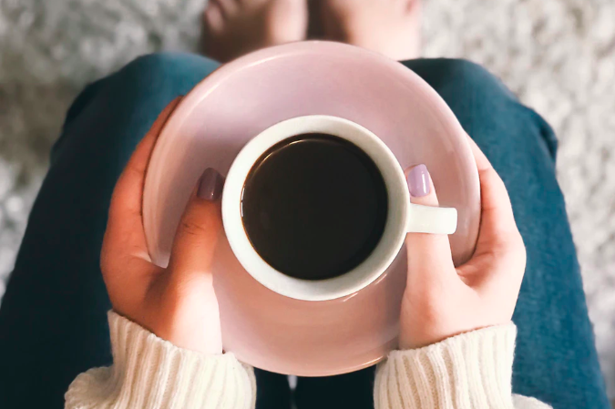 コーヒーが入ったカップを持つ女性の手