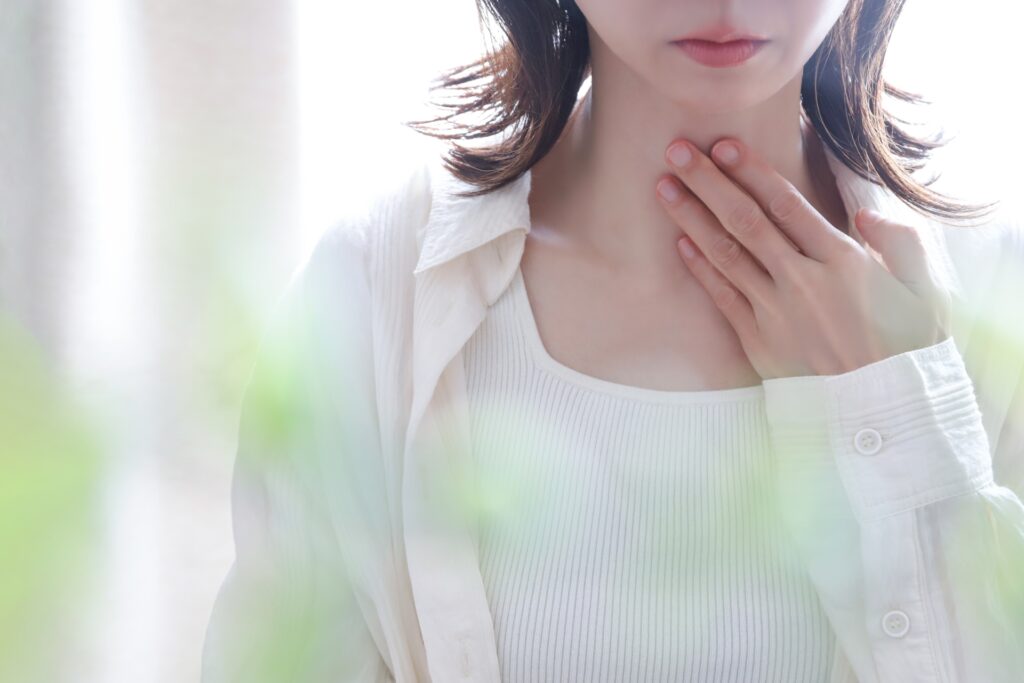 手を喉にあてる女性
