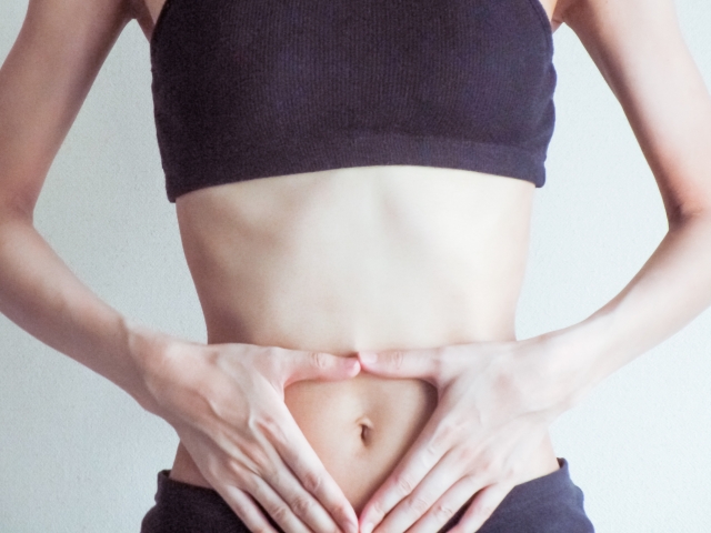 お腹に手をあてる女性