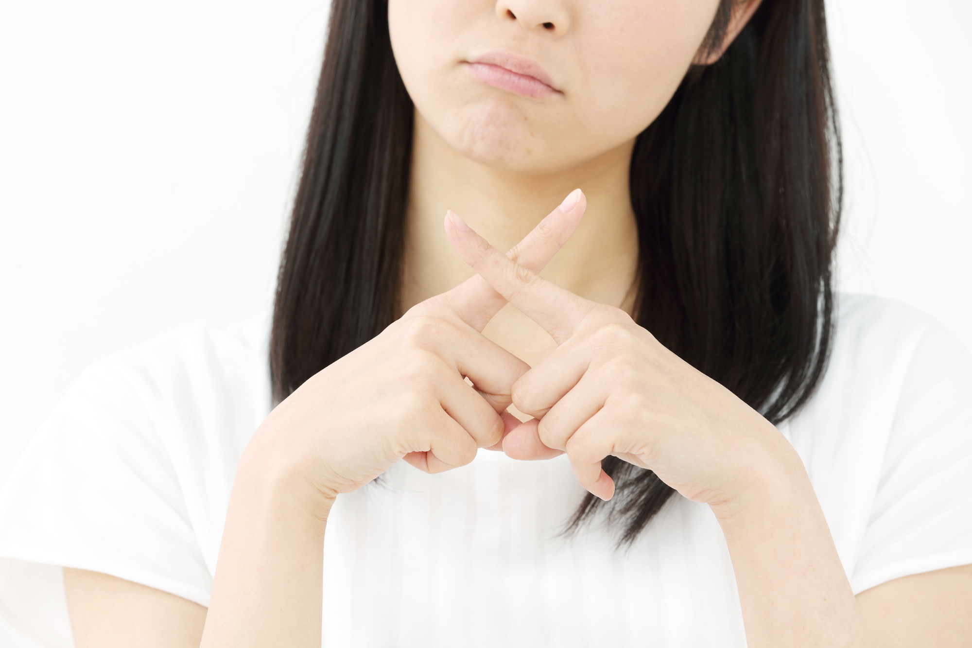 指でバツを作る女性