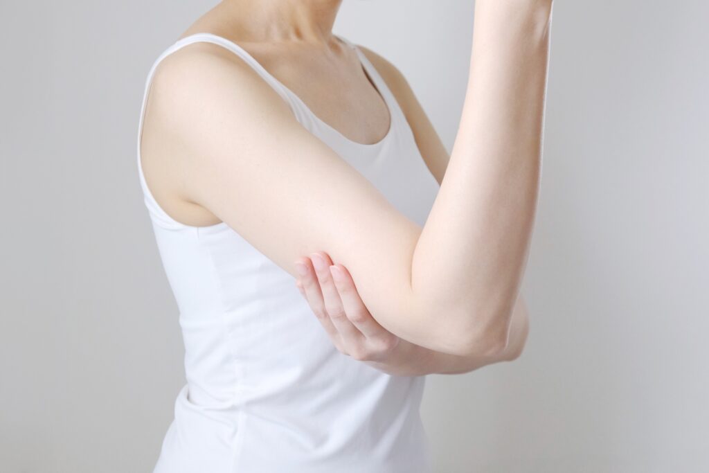 腕の筋肉を触る女性