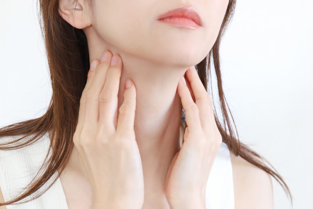 両手を首に当てる女性